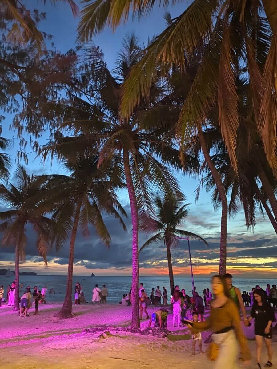 Boracay White Beach at sunset with palm trees and tourists enjoying evening nightlife in Boracay Philippines
