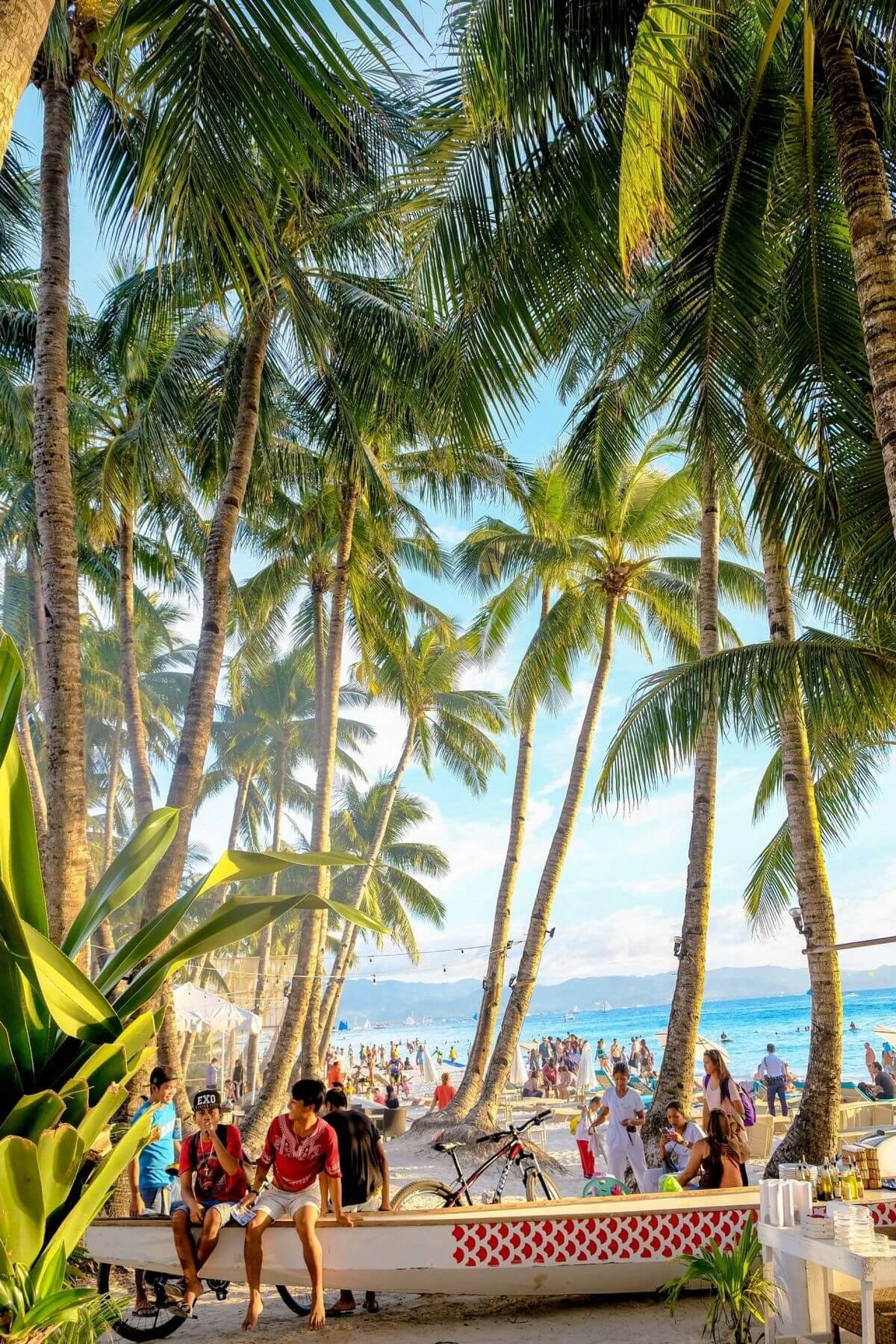 Boracay White Beach with palm trees and tourists relaxing by the seaside in Boracay Philippines