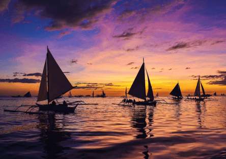 Boracay sunset paraw sailing with traditional boats on the ocean in Boracay Philippines