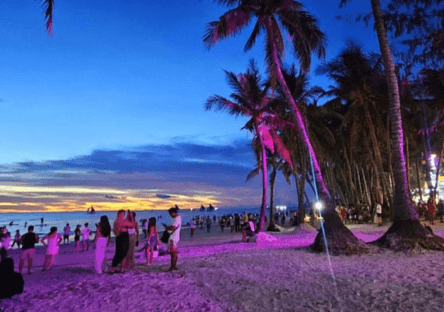 Boracay White Beach nightlife with palm trees and tourists during sunset evening in Boracay Philippines