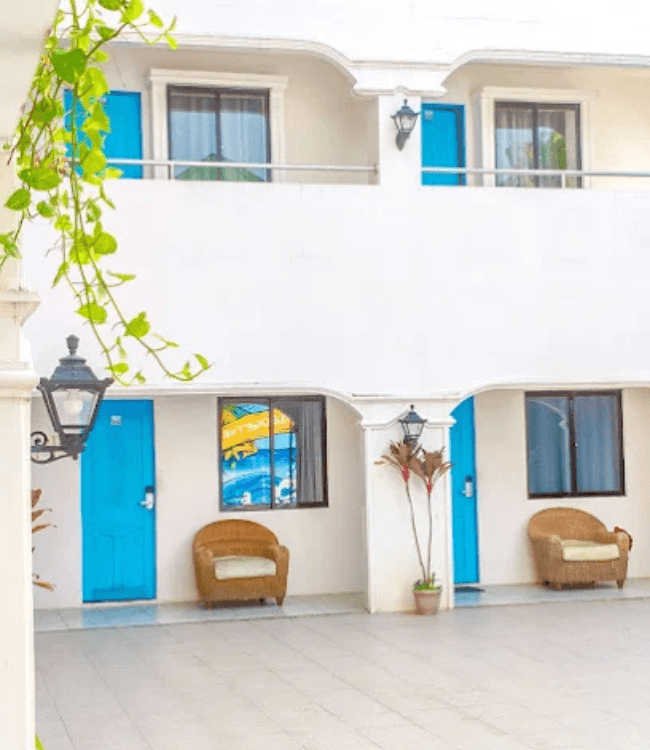 Boracay hotel exterior with white walls and blue room doors.