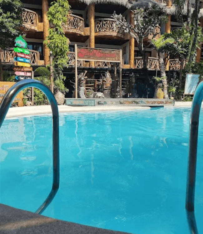 Boracay resort pool with tropical landscaping and wooden architecture.
